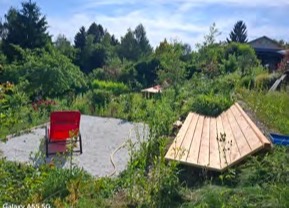 Roter Liegestuhl neben einer Holzterrasse im Garten