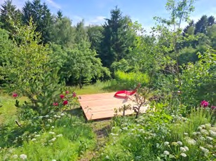 Holzdeck in der Blumenwiese, umgeben von Bäumen