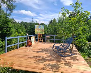 Sonnendeck aus Holz mit Schaukelstuhl und Staffelei